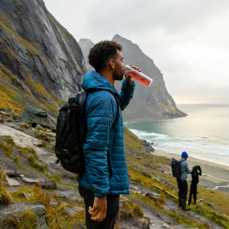 A man is seen enjoying a SuperStix while hiking in a mountainous coastal landscape.
