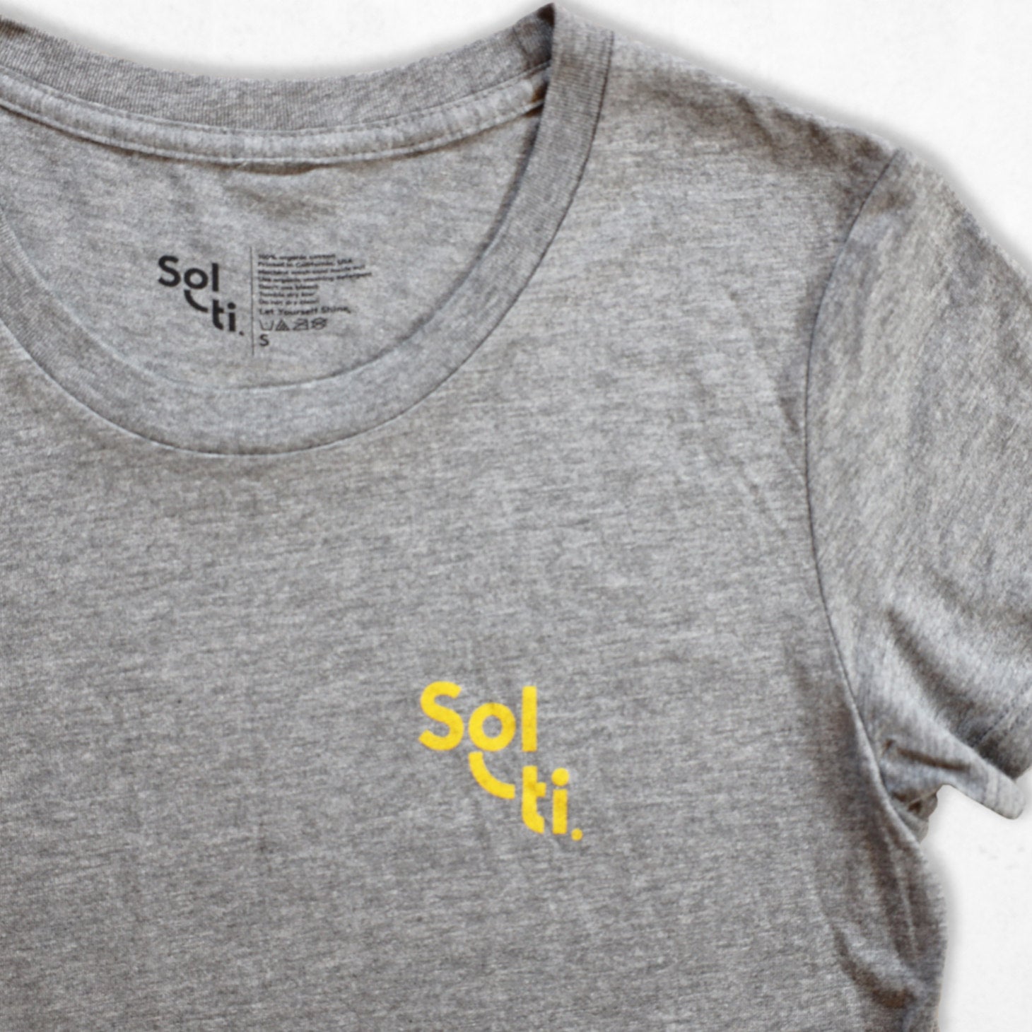 A gray organic cotton tee with the Sol-ti brand logo printed in orange on the front shown against a light background