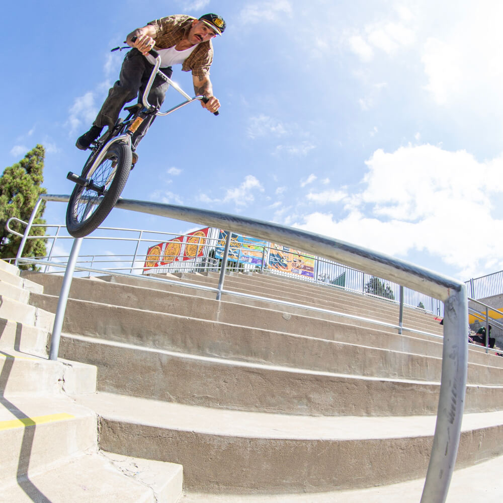Dakota Roche riding a bicycle against a blue sky with white clouds