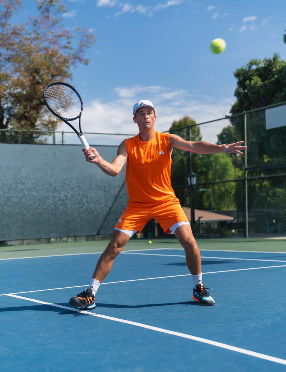 Andy Johnson playing tennis on a blue court, and holding a tennis racket