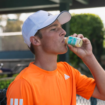 Andy Johnson drinking TROPICAL GINGER SuperShot, in a tennis court