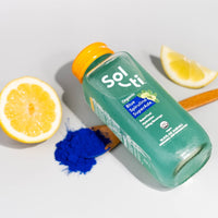 Thumbnail for Blue Spirulina SuperAde bottle next to lemons and a spoon of blue spirulina