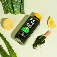 Thumbnail for a  Chlorophyll Aloe SuperAde bottle next to a lemon slices, a spoon of green spirulina and an Aloe Vera leafs