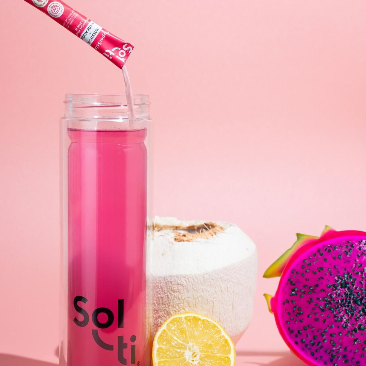 A Sol-ti Glass Bottle with Dragon Fruit Lemon SuperStix and water, next to Coconut, dragon fruit and lemon slices 