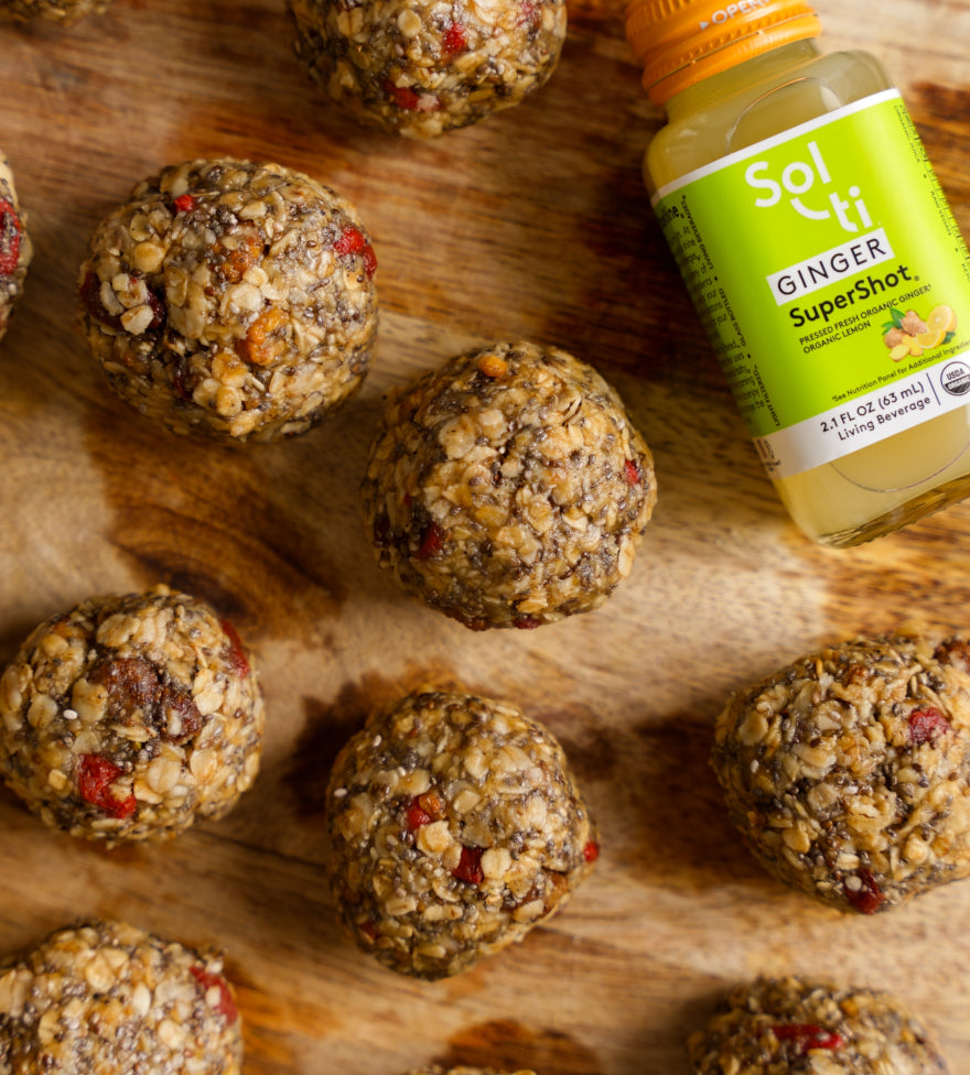 Nuts and seeds balls on a wooden surface with a Bottle of GINGER SuperShot 