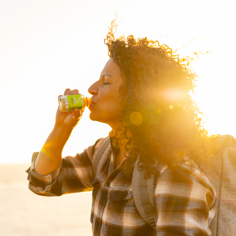 Person drinking Sol-ti GINGER SuperShot, angled front label, bright background