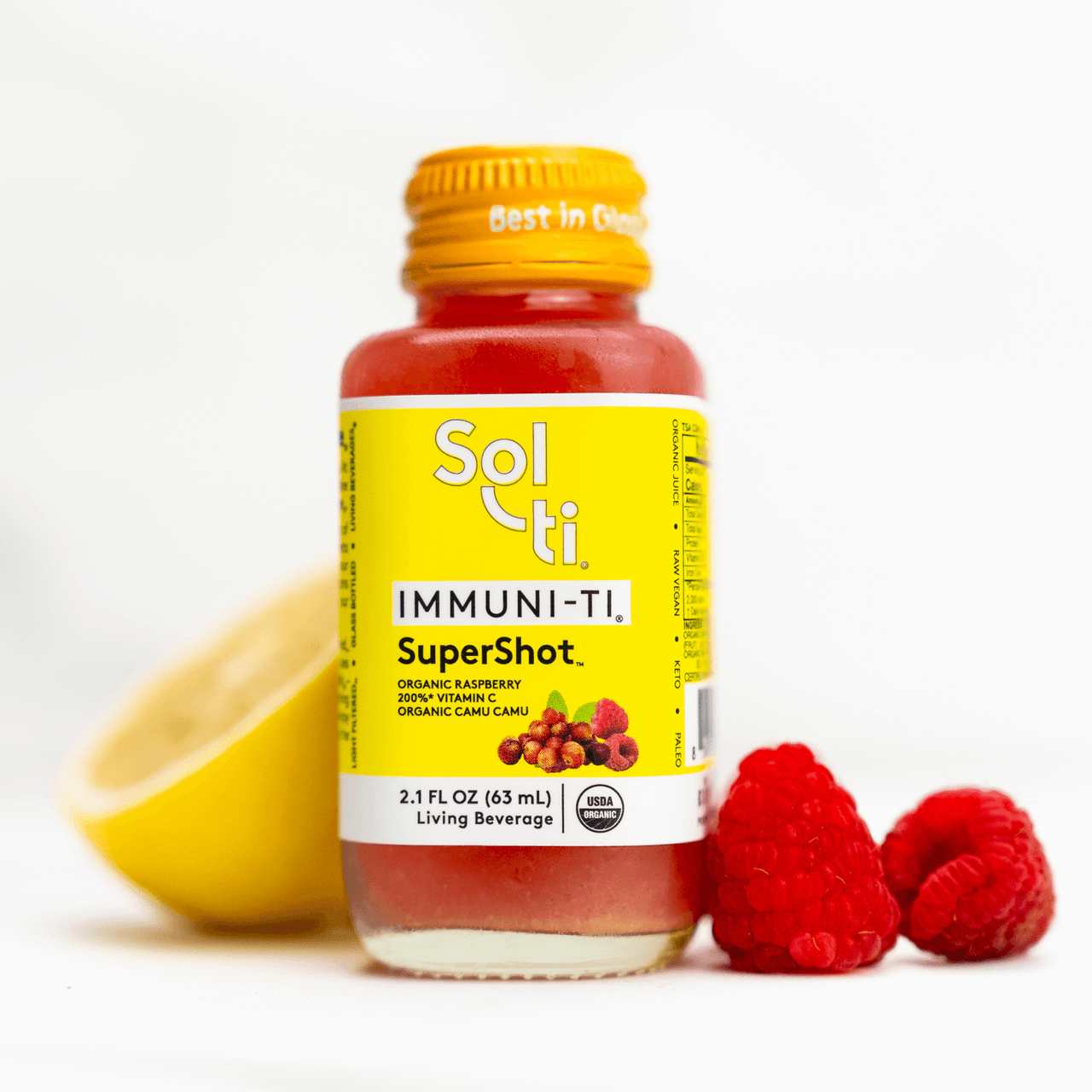 a IMMUNI-TI SuperShot bottle next to raspberries and a lemon slice
