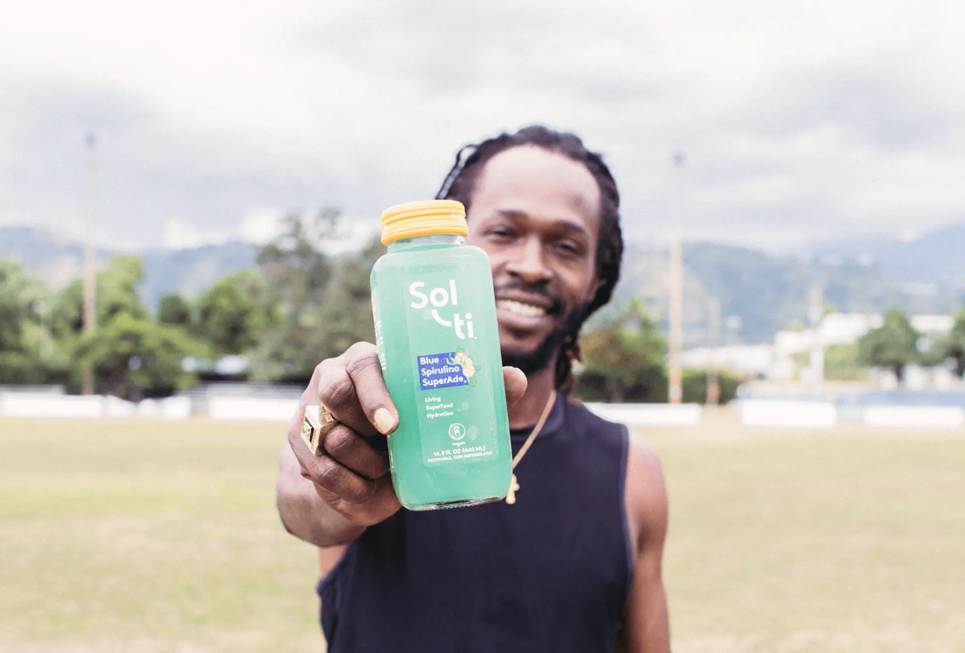Jesse Royal holding up a bottle of Blue Spirulina SuperAde