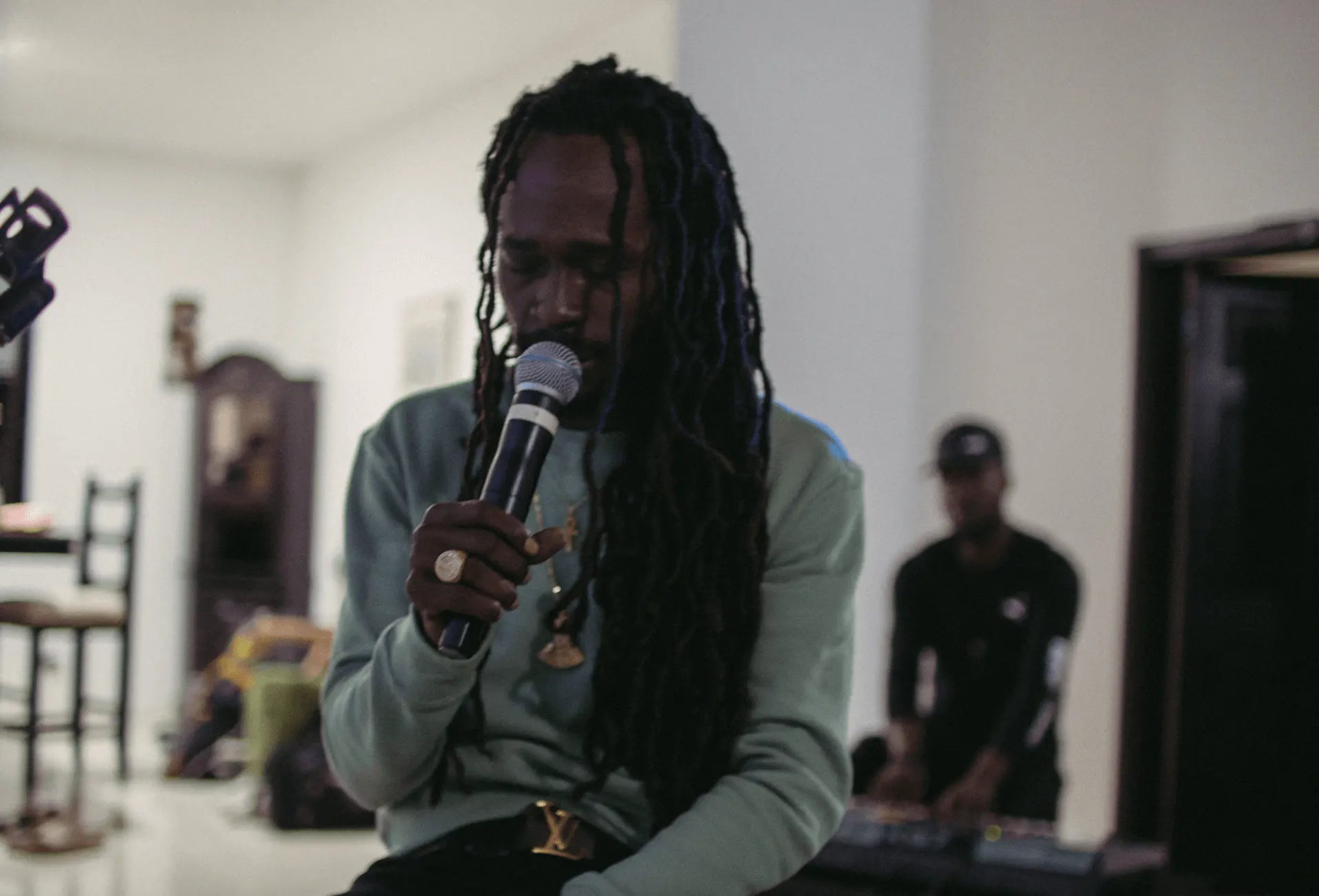 Jesse Royal sits indoors holding a microphone