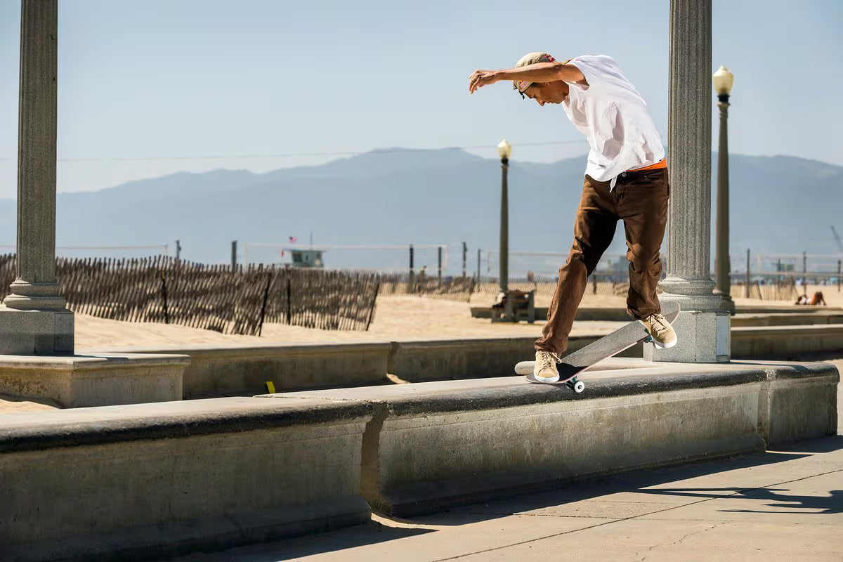 Joey Brezinski iperforms a trick on a concrete ledge at a beach boardwalk