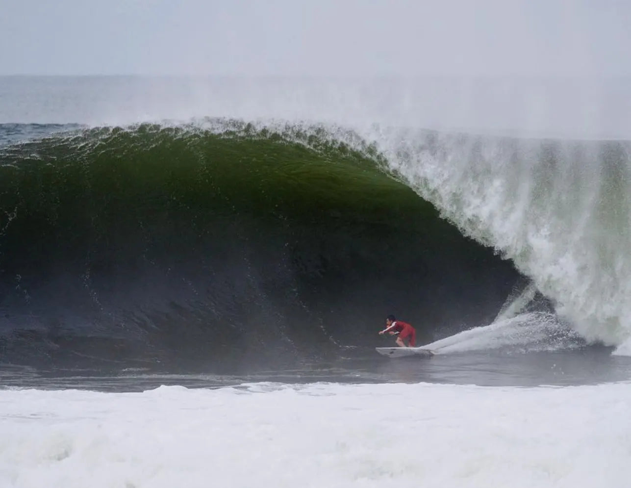 Kei Kobayashi rides inside the barrel of a large green ocean wave