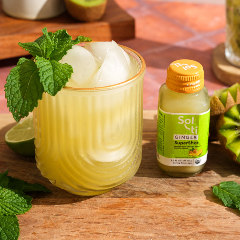 GINGER SuperShot® with a glass of Kiwi Ginger Mojito Mocktail on a wooden surface.