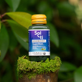 A bottle of Sol-ti MINDBOOST+ SuperShot placed on a mossy log 