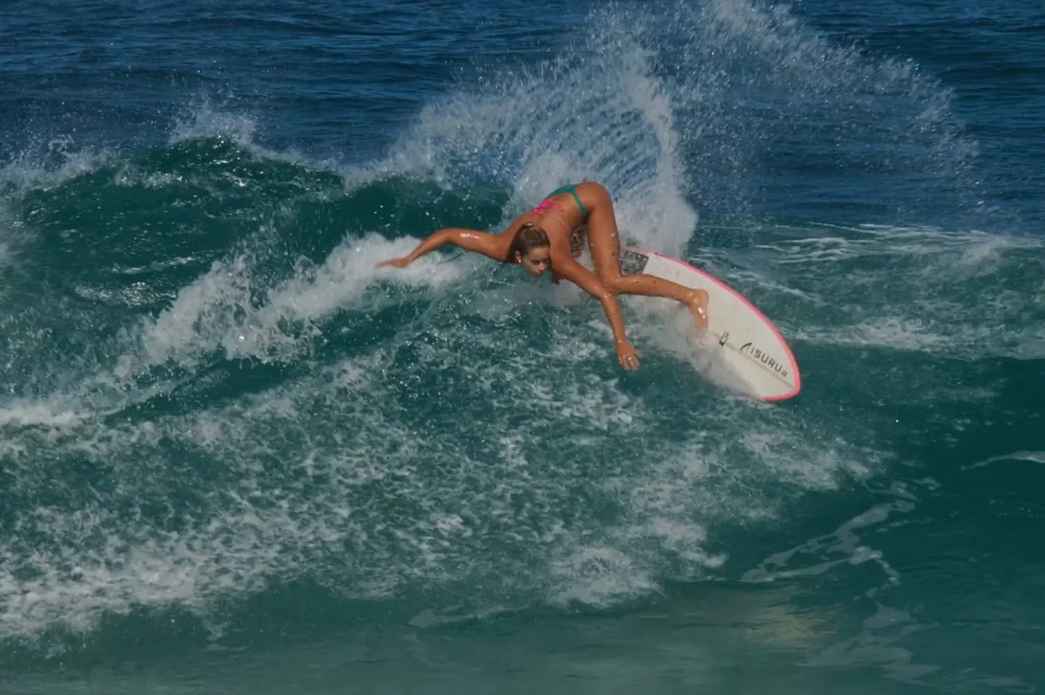 Molly Tuschen surfing on a breaking blue ocean wave.