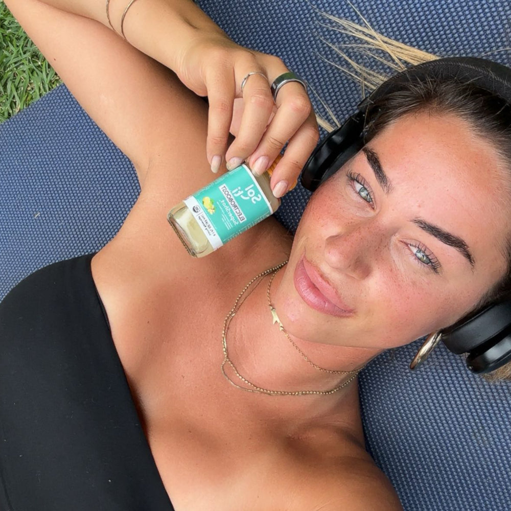 Molly Tuschen lying on a mat outdoors, holding a ELECTROBOOST SuperShot bottle 