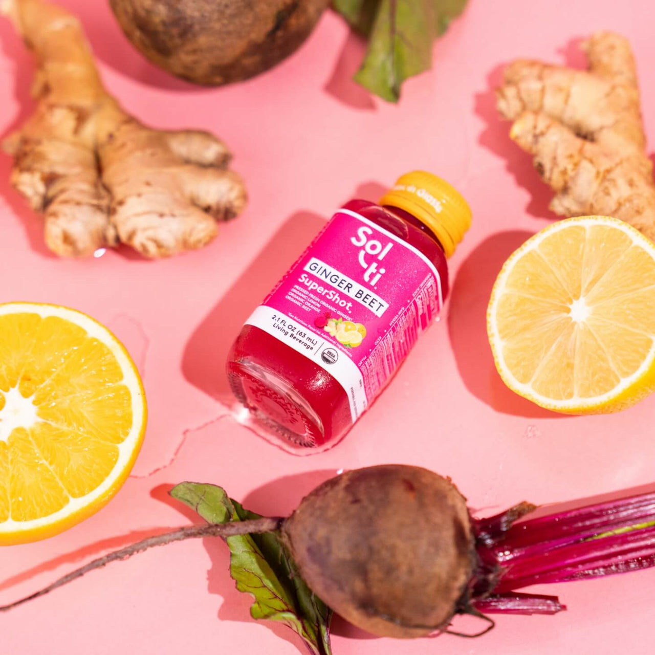 A GINGER BEET SuperShot bottle next to lemon slices, ginger root, and bbet root