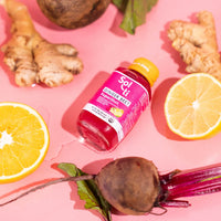 Thumbnail for A GINGER BEET SuperShot bottle next to lemon slices, ginger root, and bbet root