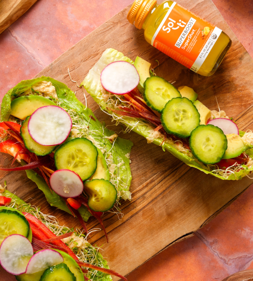 Three lettuce wraps with vegetables on a wooden board with a SUPERBOOST SuperShot.