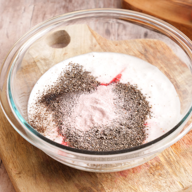 Glass bowl with chia seeds, fresh coconut milk and Strawberry Lemon SuperStix on a wooden surface