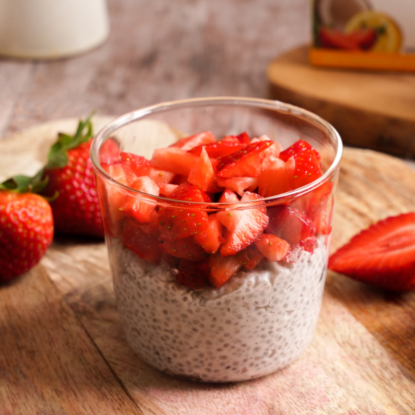 Glass of chia pudding with strawberries on a wooden surface