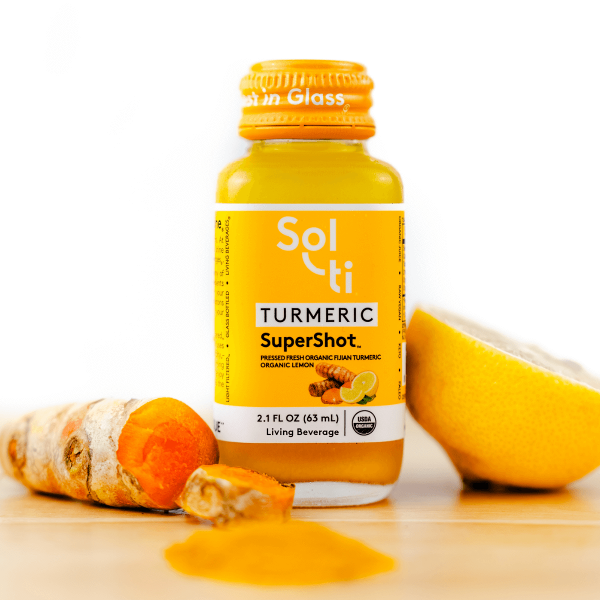 a TURMERIC SuperShot bottle with an apple, turmeric root  and a lemon slice 