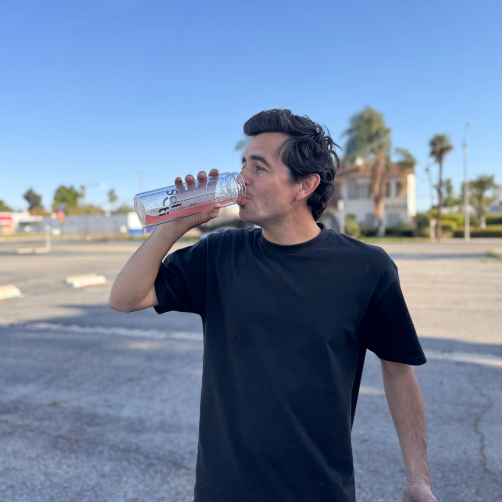 Trevor McClung drinkingSuperStix, standing in an outdoor paved area