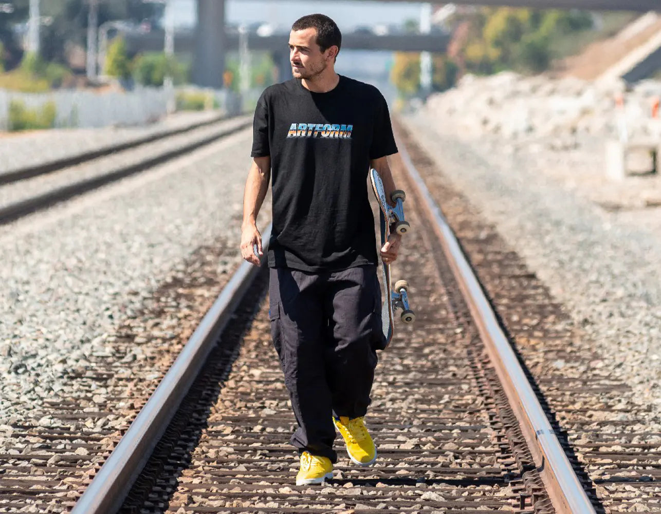 Trevor_McClung walking on railroad tracks while holding a skateboard