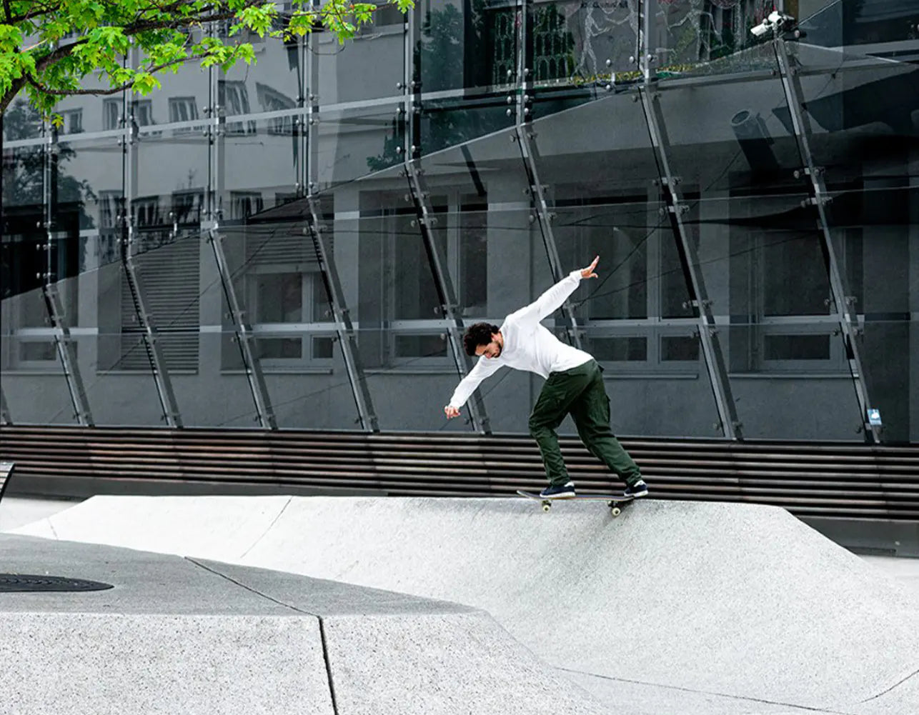 Trevor McClung performs a trick on a concrete ramp in front of a modern glass building