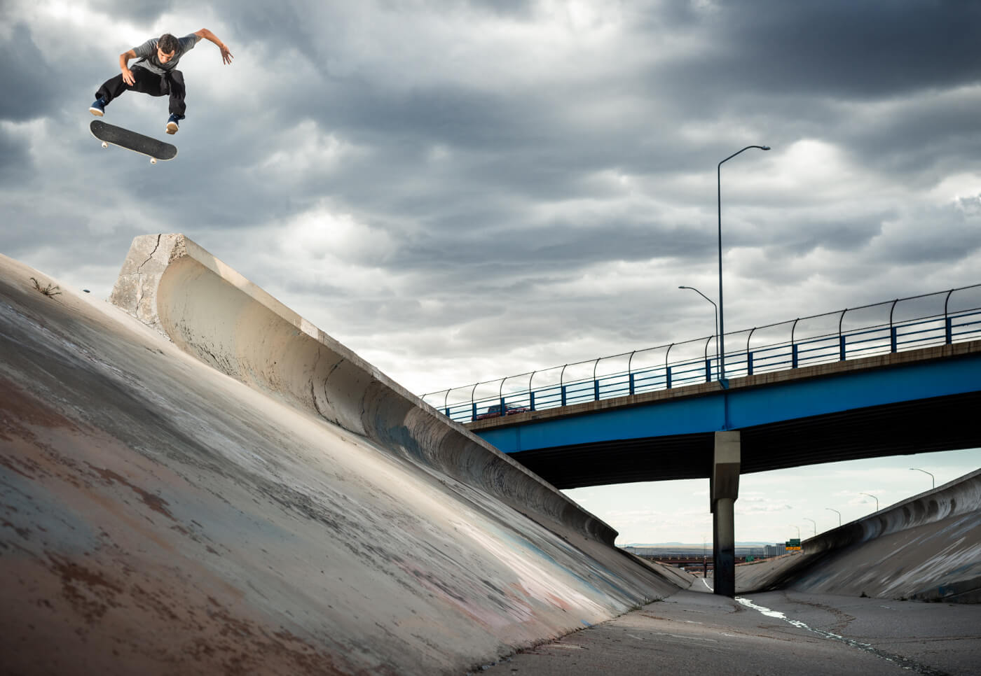 Trevor McClung mid-air performing a trick above a concrete ramp under an overpass bridge