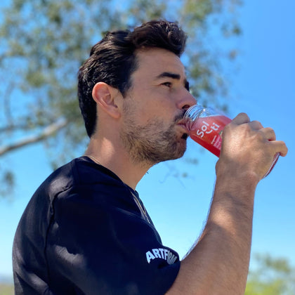 Trevor McClung drinking a SuperAde in outdoors against a blue sky and tree 